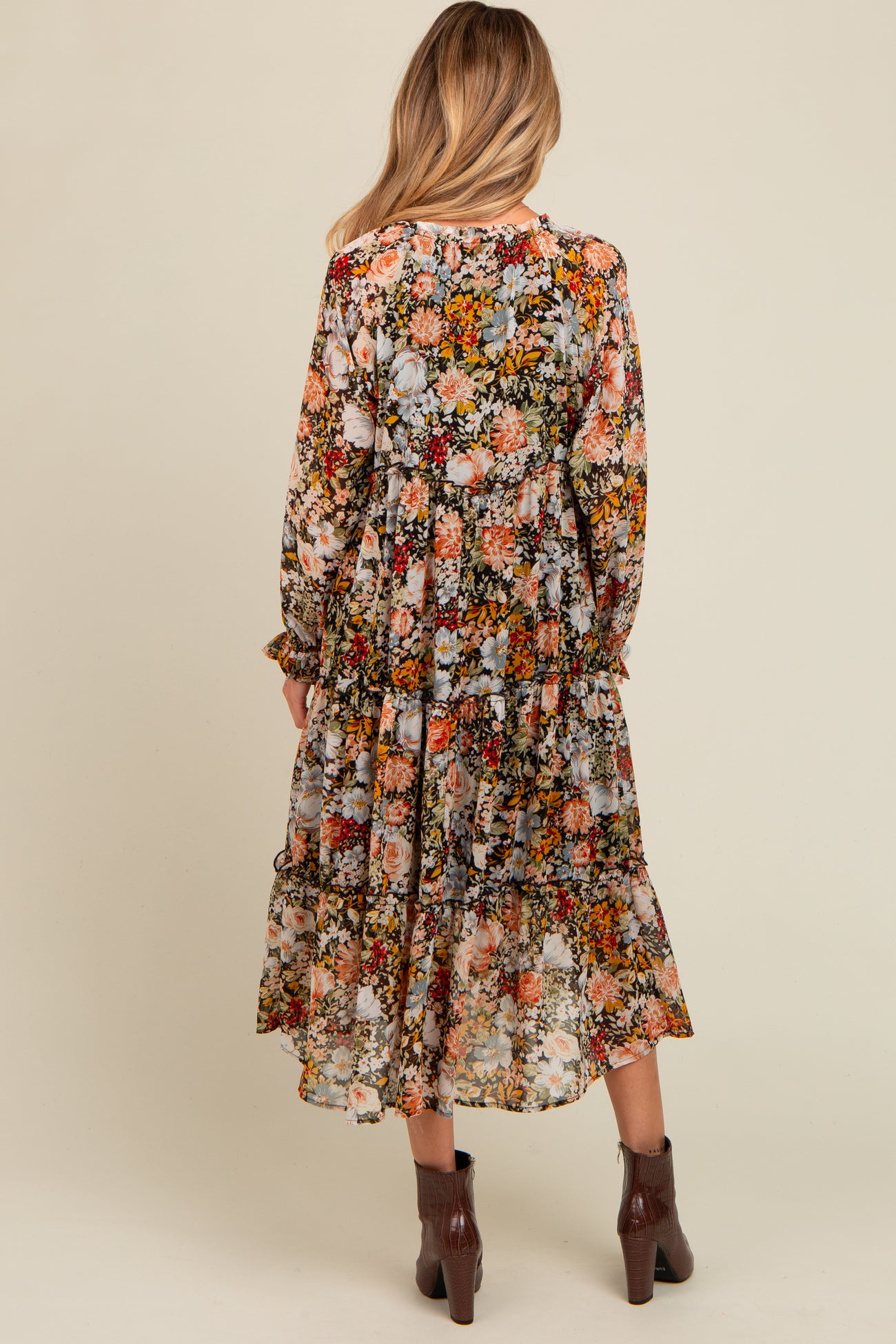 woman wearing a floral patterned maternity maxi dress with long sleeves and tiered ruffles from the back