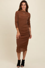 woman wearing a brown long sleeve bodycon dress with ruching details and black heeled ankle boots