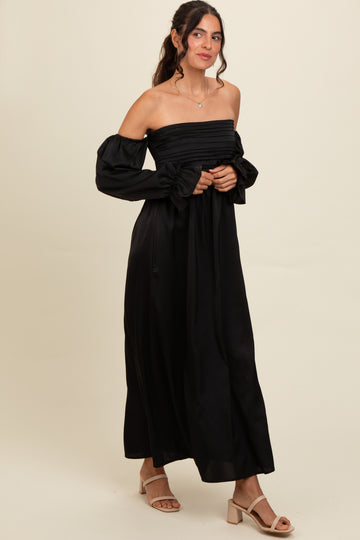 woman wearing a black off-the-shoulder maxi dress with puff sleeves and a fitted bodice