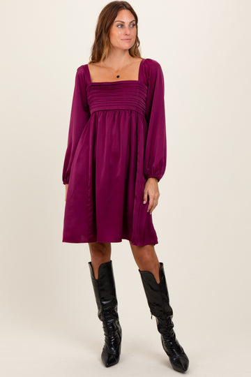 woman wearing a plum square neck mini dress with puff sleeves and a gathered bodice, paired with black knee-high boots
