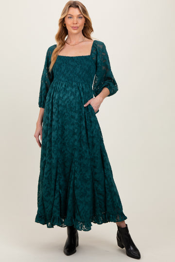 woman wearing a teal maternity dress with a square neckline, puff sleeves, and a relaxed fit, featuring a smocked bodice and pockets