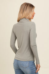 woman wearing a light gray long sleeve turtleneck top and blue jeans, posed from the back