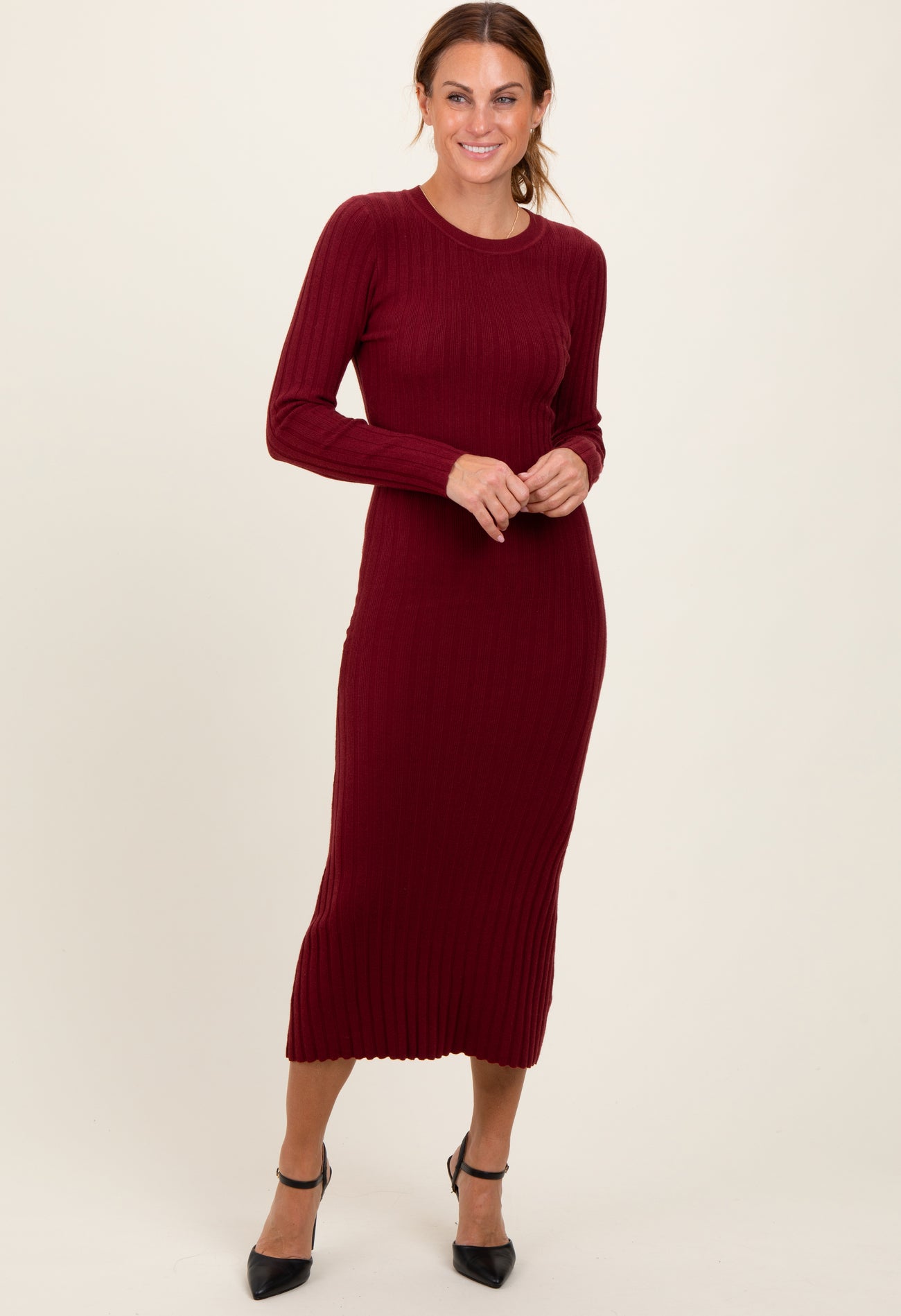 woman wearing a burgundy long sleeve ribbed midi dress and black heeled shoes