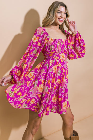 woman wearing a bright pink floral print mini dress with puff sleeves and a square neckline