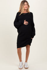woman wearing a black cable knit maternity dress with long sleeves and holding her baby bump