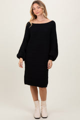 woman wearing a black cable knit sweater dress with balloon sleeves and creamy ankle boots