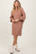 woman wearing a blush cable-knit sweater dress with balloon sleeves and white ankle boots