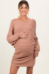 woman wearing a beige cable knit maternity dress and holding her baby bump