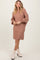 woman wearing a blush cable-knit sweater dress with balloon sleeves and white ankle boots