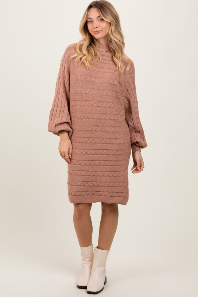 woman wearing a blush pink cable knit sweater dress with balloon sleeves and a slightly longer back hem