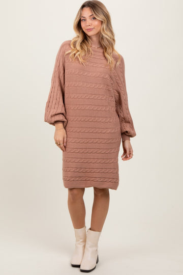woman wearing a blush pink cable knit sweater dress with balloon sleeves and a slightly longer back hem