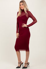 woman wearing a burgundy long sleeve dress with sheer mesh details and a fitted silhouette