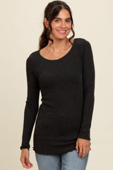 woman wearing a black long sleeve ribbed top with a scoop neckline and scalloped hem, smiling at the camera