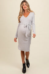 woman wearing a grey long sleeve maternity dress with a tie waist and a visible baby bump
