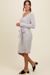 woman wearing a light grey long sleeve sweater dress with a tie waist detail and heeled sandals