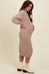 woman wearing a beige knit maternity dress with long sleeves and a baby bump, standing sideways