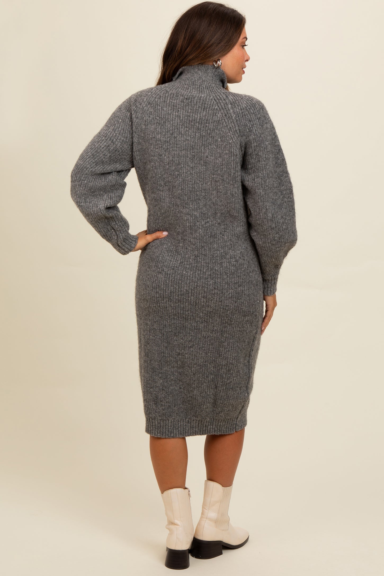 woman wearing a gray knitted maternity dress with a high collar and balloon sleeves, styled with ankle boots
