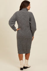 woman wearing a gray knitted maternity dress with a high collar and balloon sleeves, styled with ankle boots