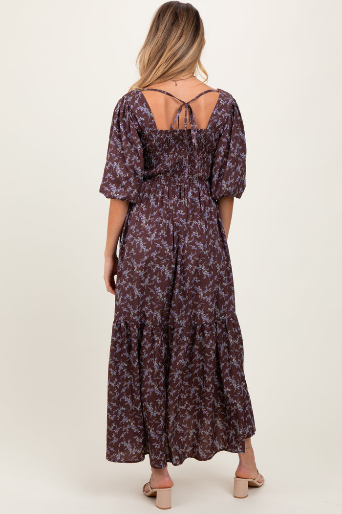 woman wearing a brown floral maternity maxi dress with puff sleeves and a smocked back, showing part of her baby bump