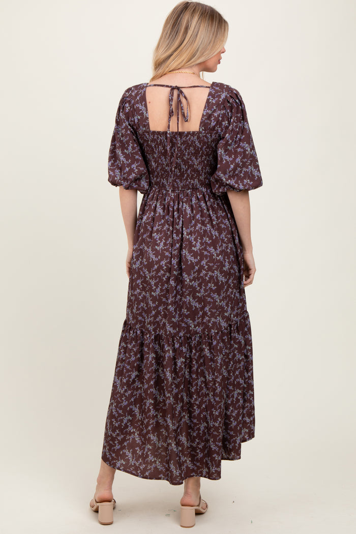 woman wearing a brown floral maxi dress with puff sleeves and a tie-back detail