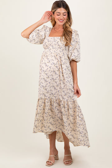 woman wearing a floral maternity dress with puff sleeves and a tiered hem, showing her baby bump
