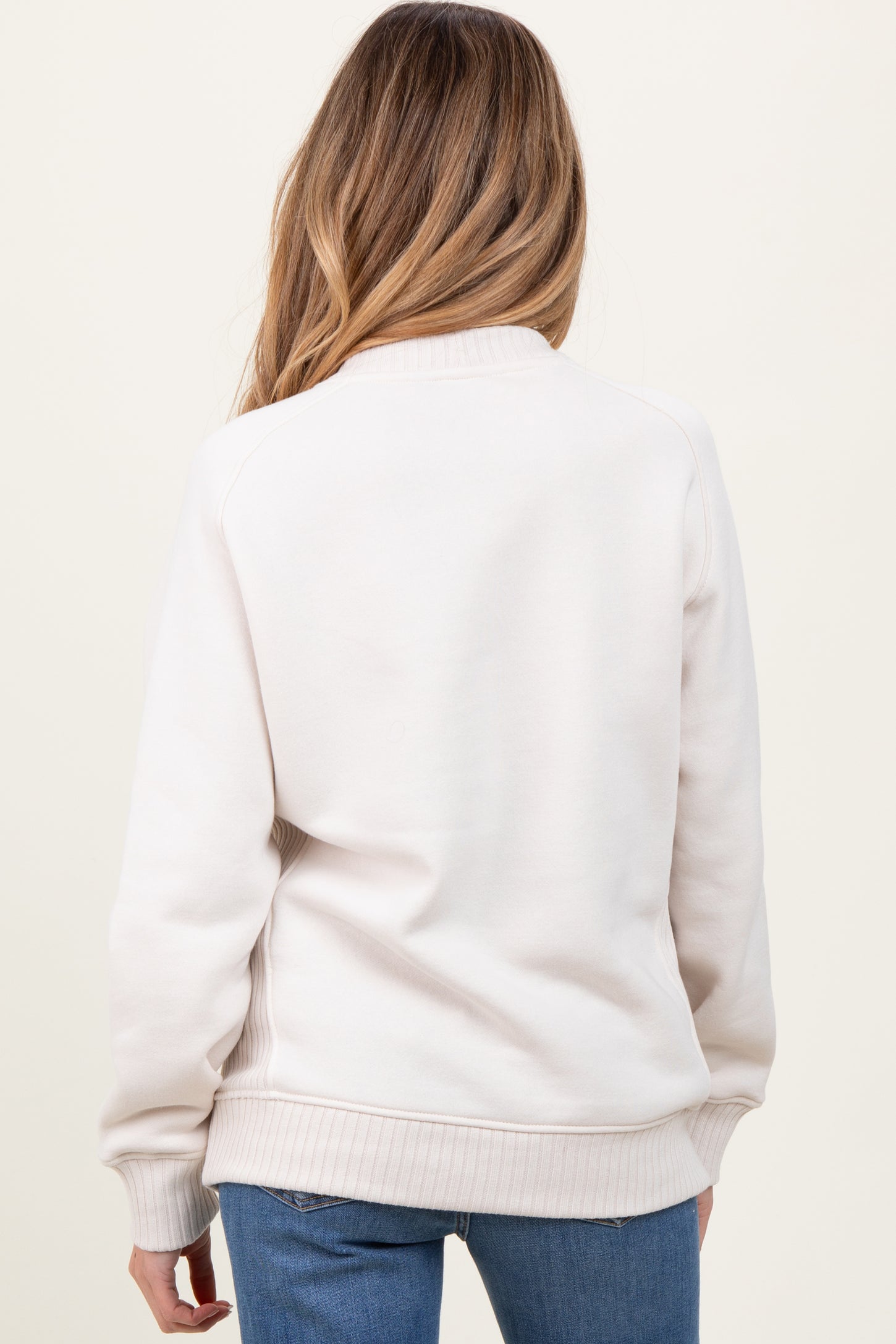 woman wearing a light beige maternity sweatshirt with a cozy fit, viewed from the back