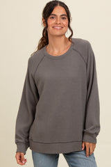 woman wearing a gray long sleeve waffle knit sweatshirt and smiling
