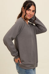 woman wearing a gray long sleeve sweatshirt with textured fabric and relaxed fit, posing with hand on her hair