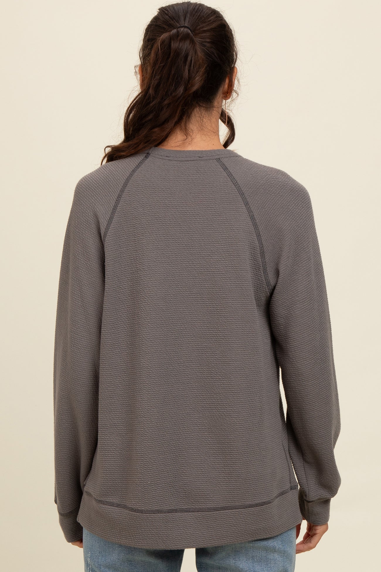 woman wearing a gray long sleeve sweatshirt with a relaxed fit and raglan sleeves, viewed from the back