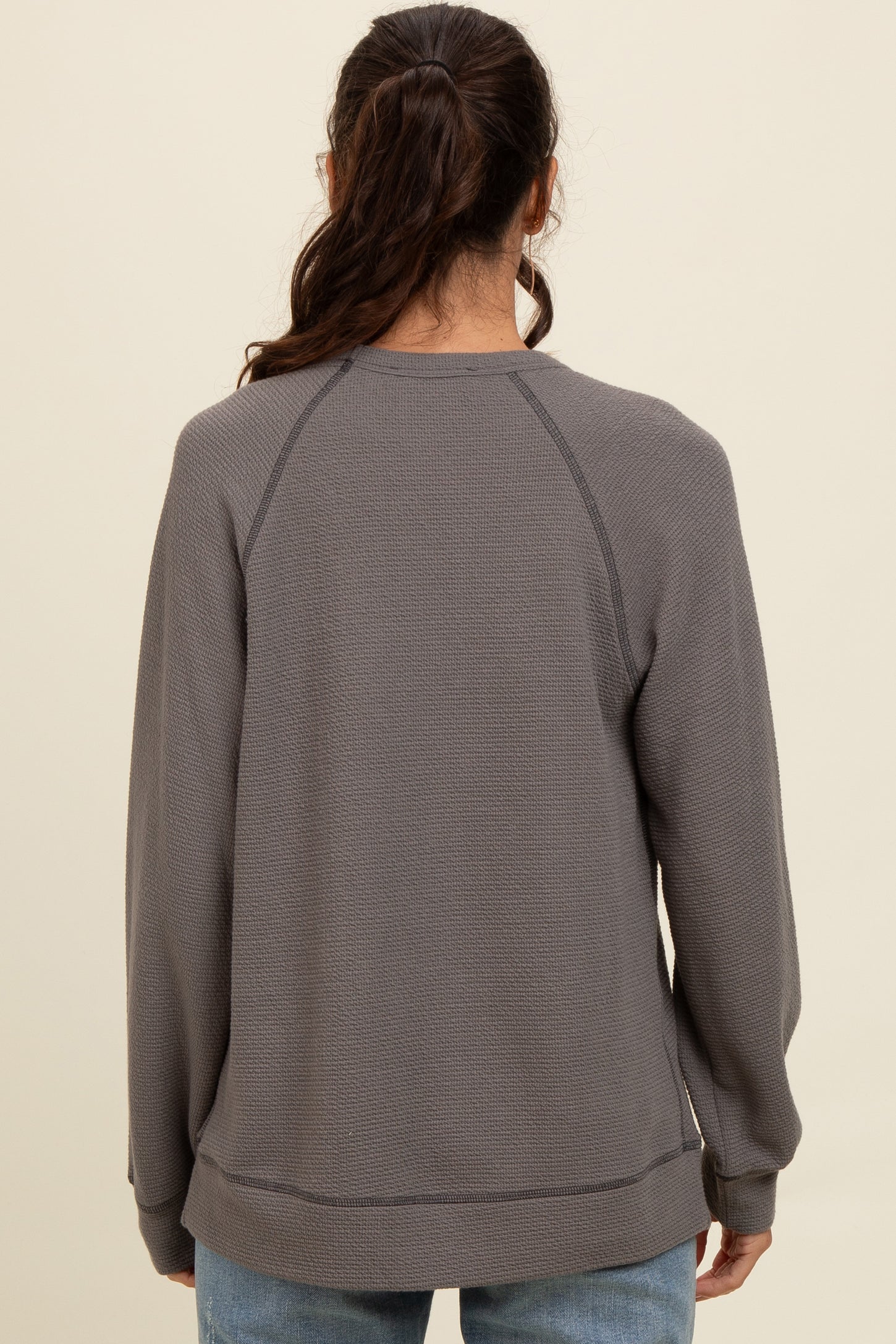 woman wearing a gray long sleeve sweatshirt with a relaxed fit and raglan sleeves, viewed from the back