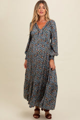 woman wearing a navy blue floral maternity maxi dress with long sleeves and a v-neckline, showcasing her baby bump