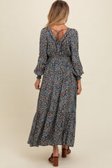 woman wearing a floral print maternity maxi dress with puff sleeves and a keyhole back detail