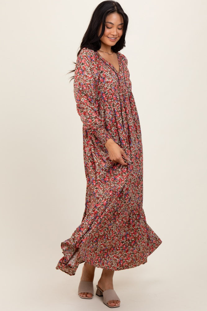 woman wearing a long floral print maxi dress with a v-neckline and long sleeves, standing and smiling