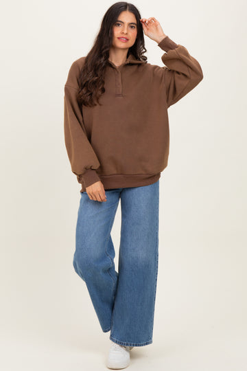 woman wearing a brown oversized pullover sweatshirt with a collar and wide-leg blue jeans