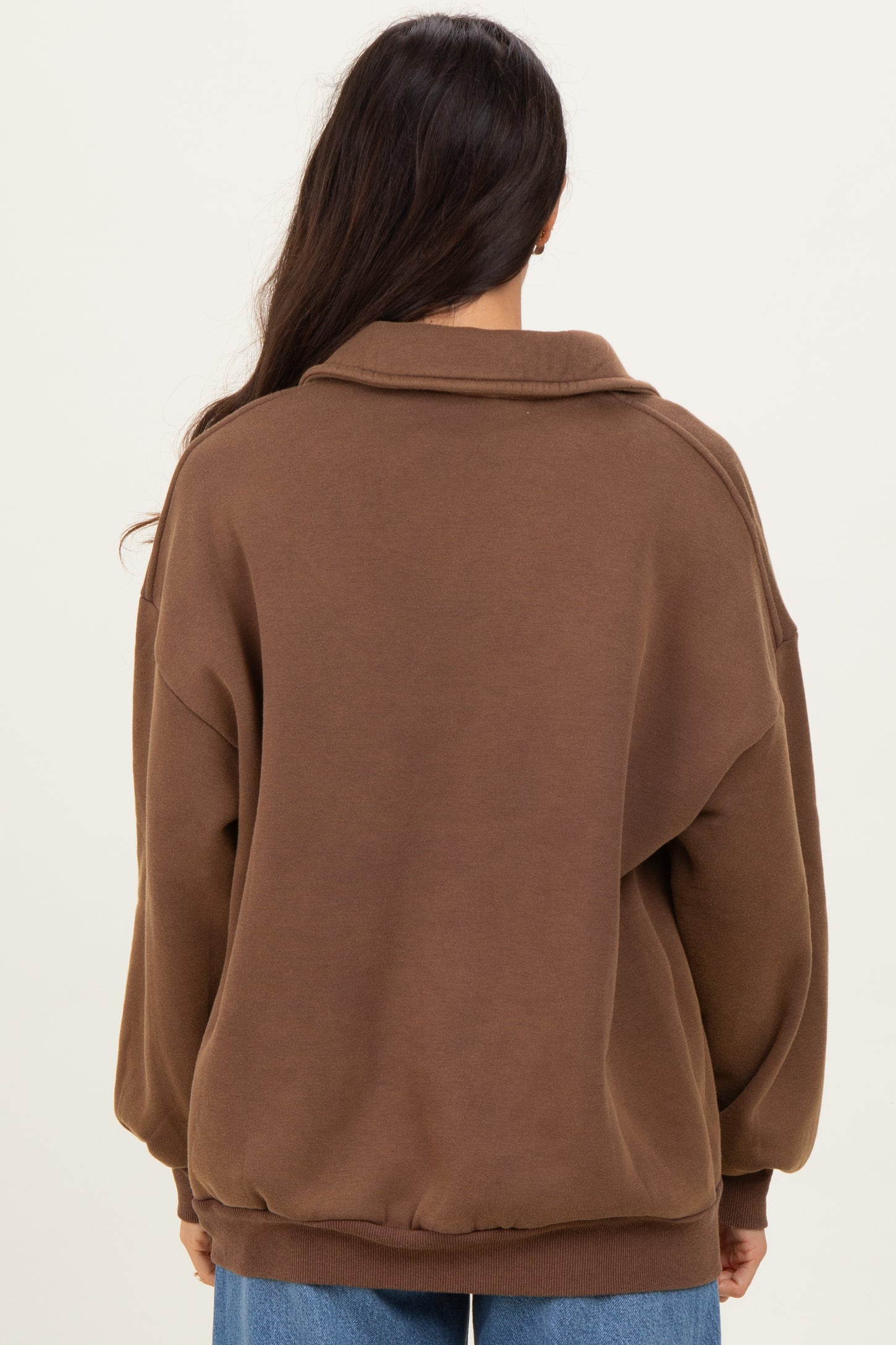 woman wearing a brown oversized sweatshirt with a collar, seen from the back