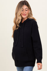 woman wearing a black maternity hoodie with a front pocket and a relaxed fit, showcasing a baby bump