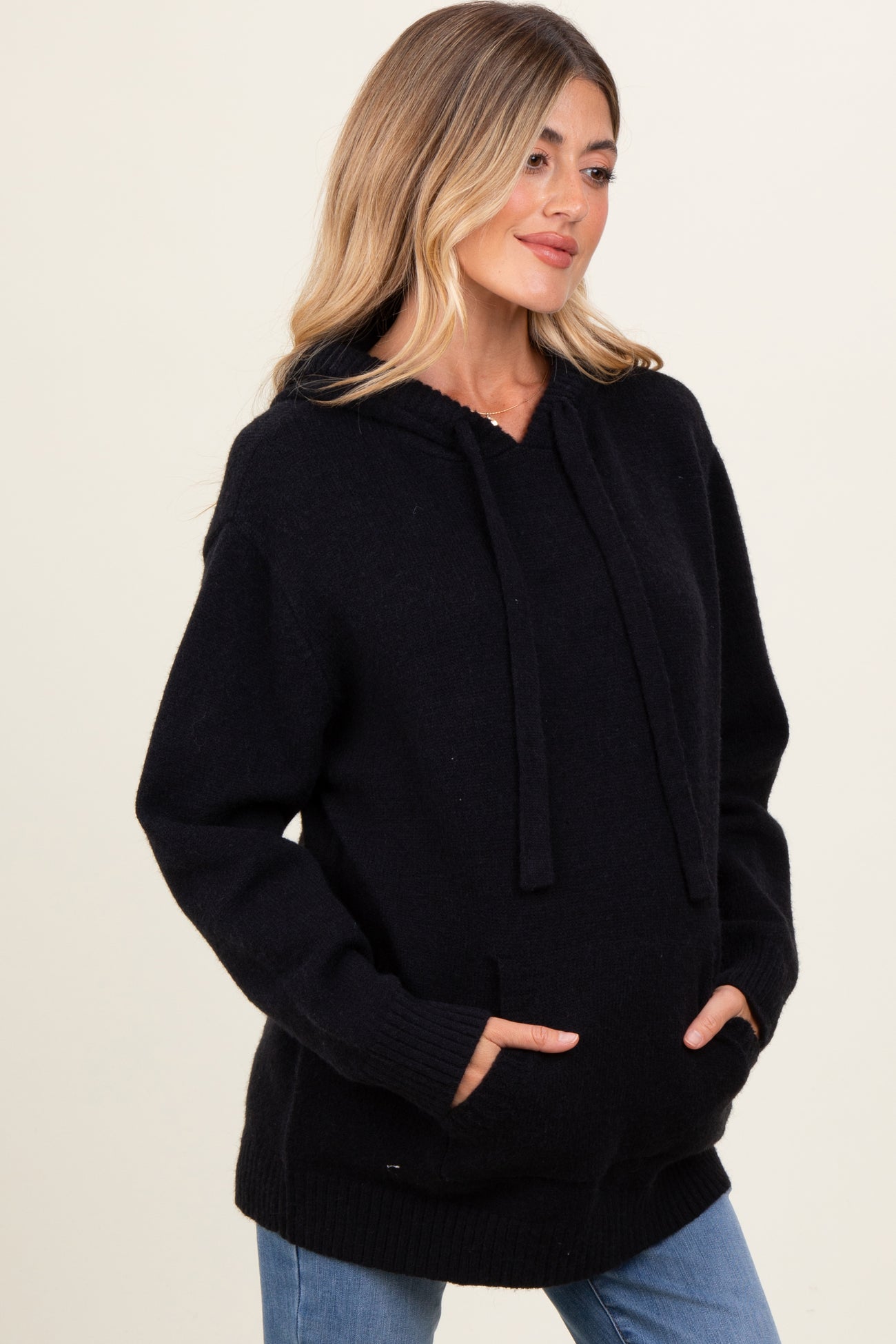 woman wearing a black maternity hoodie with a front pocket and loose fit, showing her baby bump