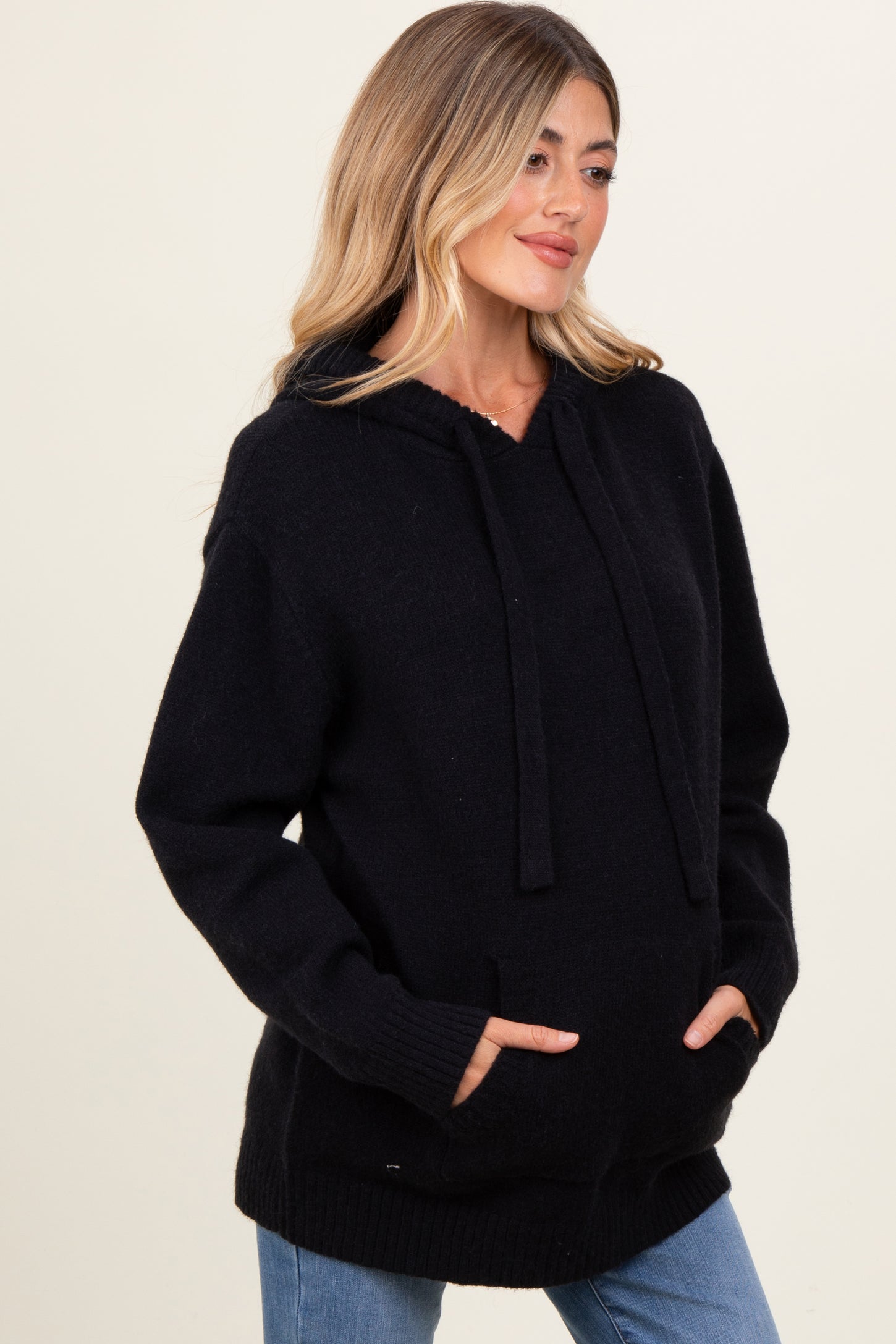 woman wearing a black maternity hoodie with a front pocket and loose fit, showing her baby bump