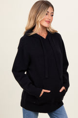 woman wearing a black maternity hoodie with a front pocket and loose fit, showing her baby bump