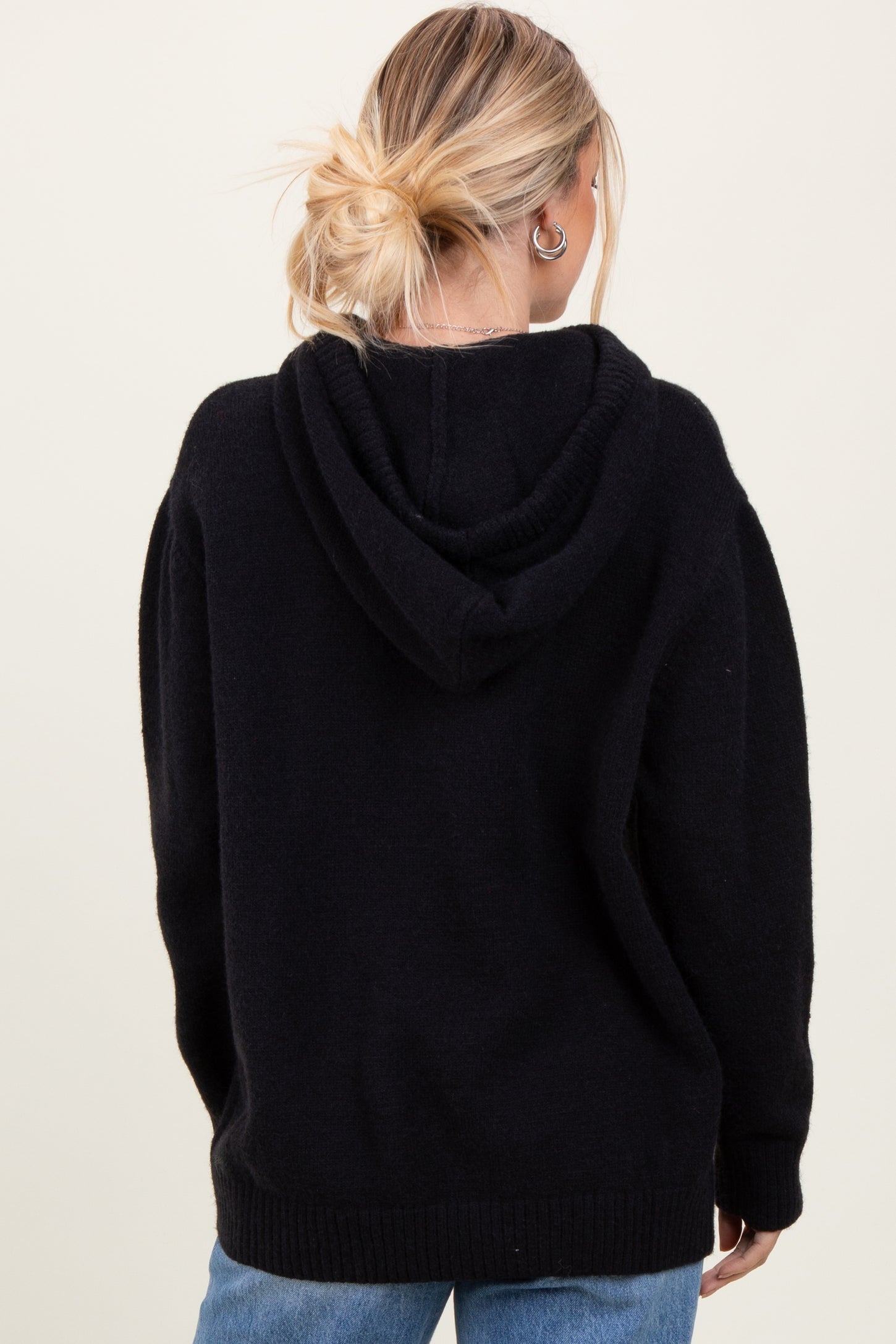 woman wearing a black oversized hoodie with a relaxed fit and a hood, shown from the back