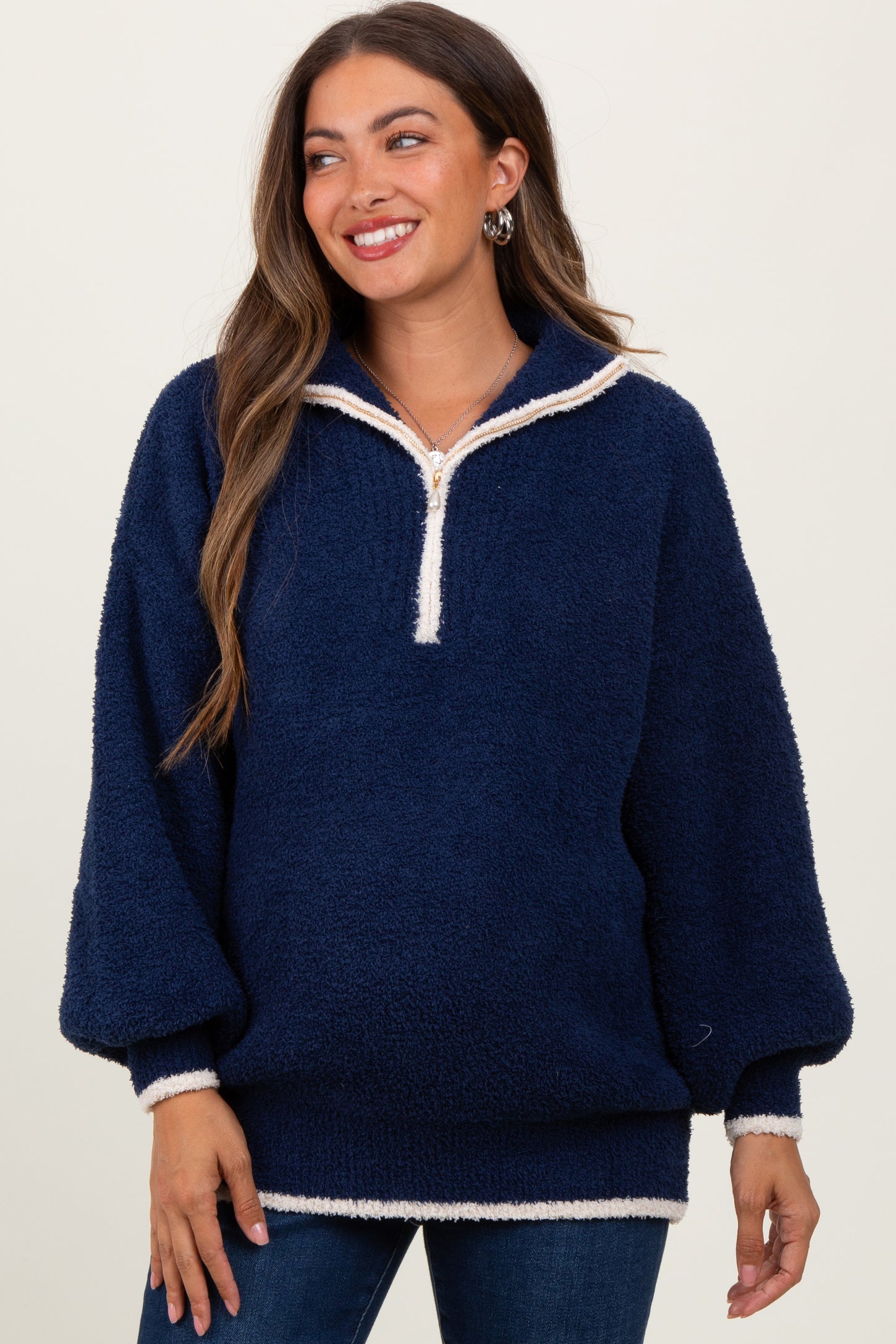 woman wearing a navy blue maternity pullover with a half zip and cream trim, smiling and styled for comfort