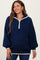 woman wearing a navy blue maternity pullover with a half zip and cream trim, smiling and styled for comfort