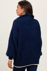 woman wearing a navy blue maternity sweater with a cozy texture and a high collar, viewed from the back