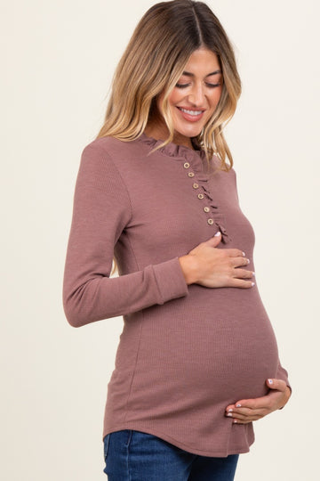 woman wearing a mauve maternity ribbed top with ruffle detail and buttons, showing her baby bump