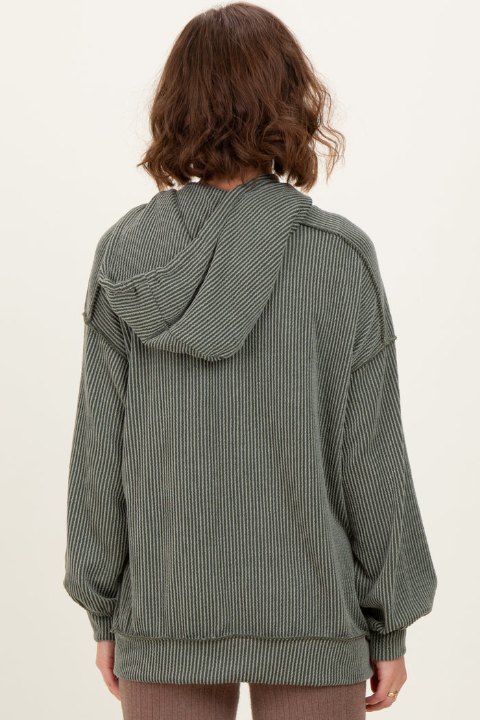 woman wearing a green striped oversized hoodie with a hood and long sleeves, seen from the back