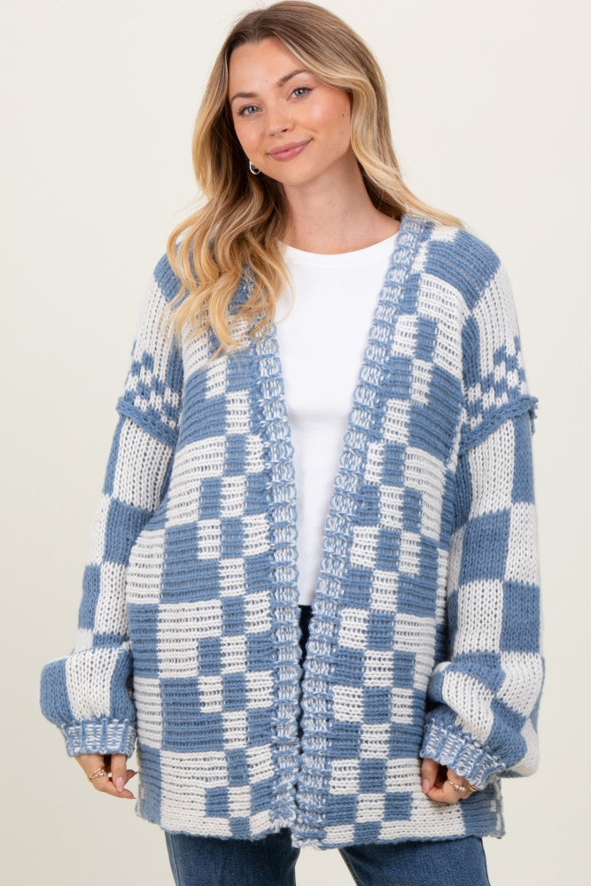 woman wearing a blue and white checked knit cardigan over a white top and jeans