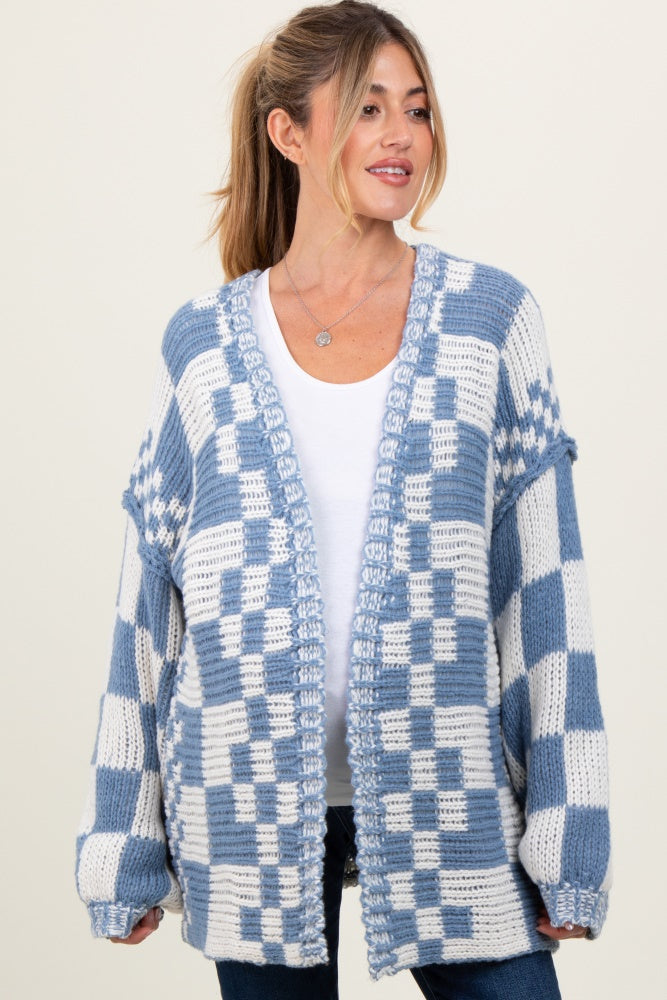 woman wearing a blue and white checkered maternity cardigan over a white top, with her hair styled in a ponytail