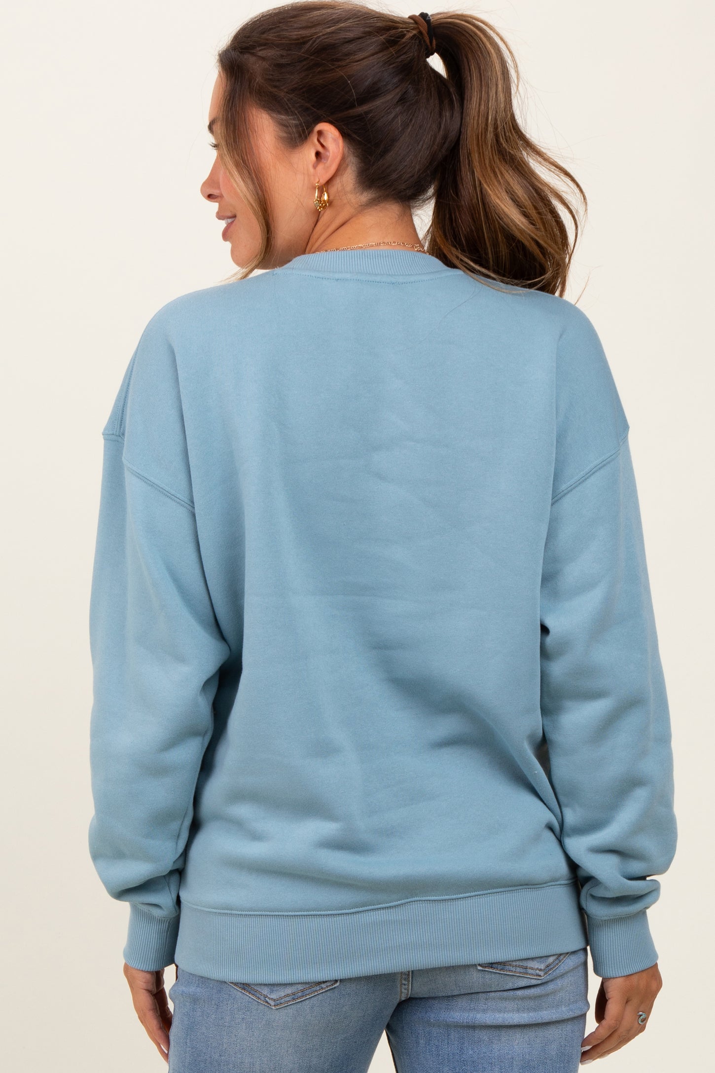 woman wearing a blue sweatshirt from the back in a maternity style with a relaxed fit and ribbed cuffs