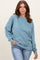 woman wearing a relaxed fit light blue sweatshirt with long sleeves and a round neckline paired with jeans