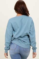woman wearing a light blue oversized sweatshirt with a relaxed fit and ribbed cuffs, viewed from the back